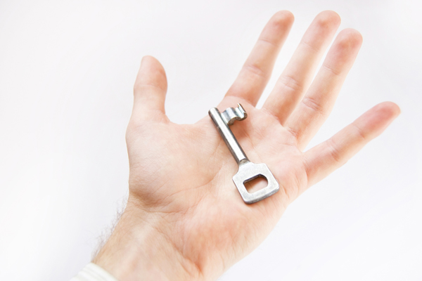 Mano de Mujer de negocios ambiciosa sonriendo, representando la llave del éxito profesional y garra comercial
